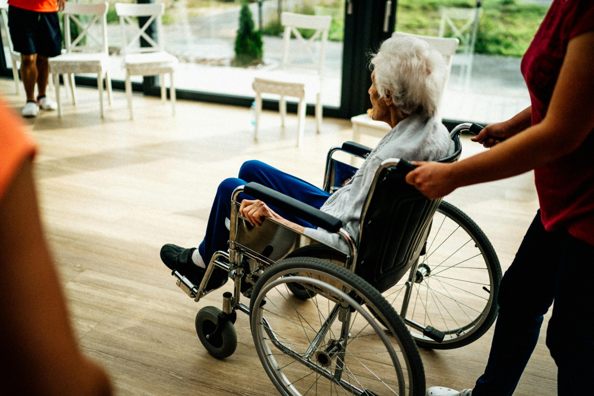 Eine Pflegekraft unterstützt einen älteren Menschen im Rollstuhl in einem Pflegeheim in Prag, Tschechische Republik.