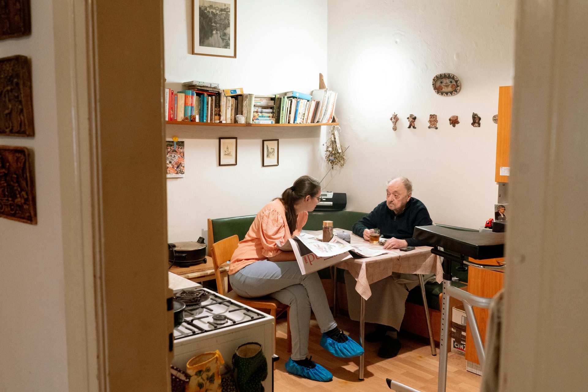 Herzliche Szene: Eine Pflegekraft und ein Senior unterhalten sich freundlich bei einer Tasse Kaffee in Prag.