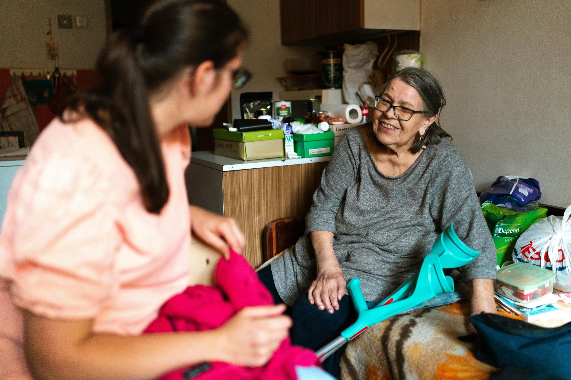 Eine Pflegekraft hilft einer älteren Dame mit Krücken in einer gemütlichen Prager Wohnung.